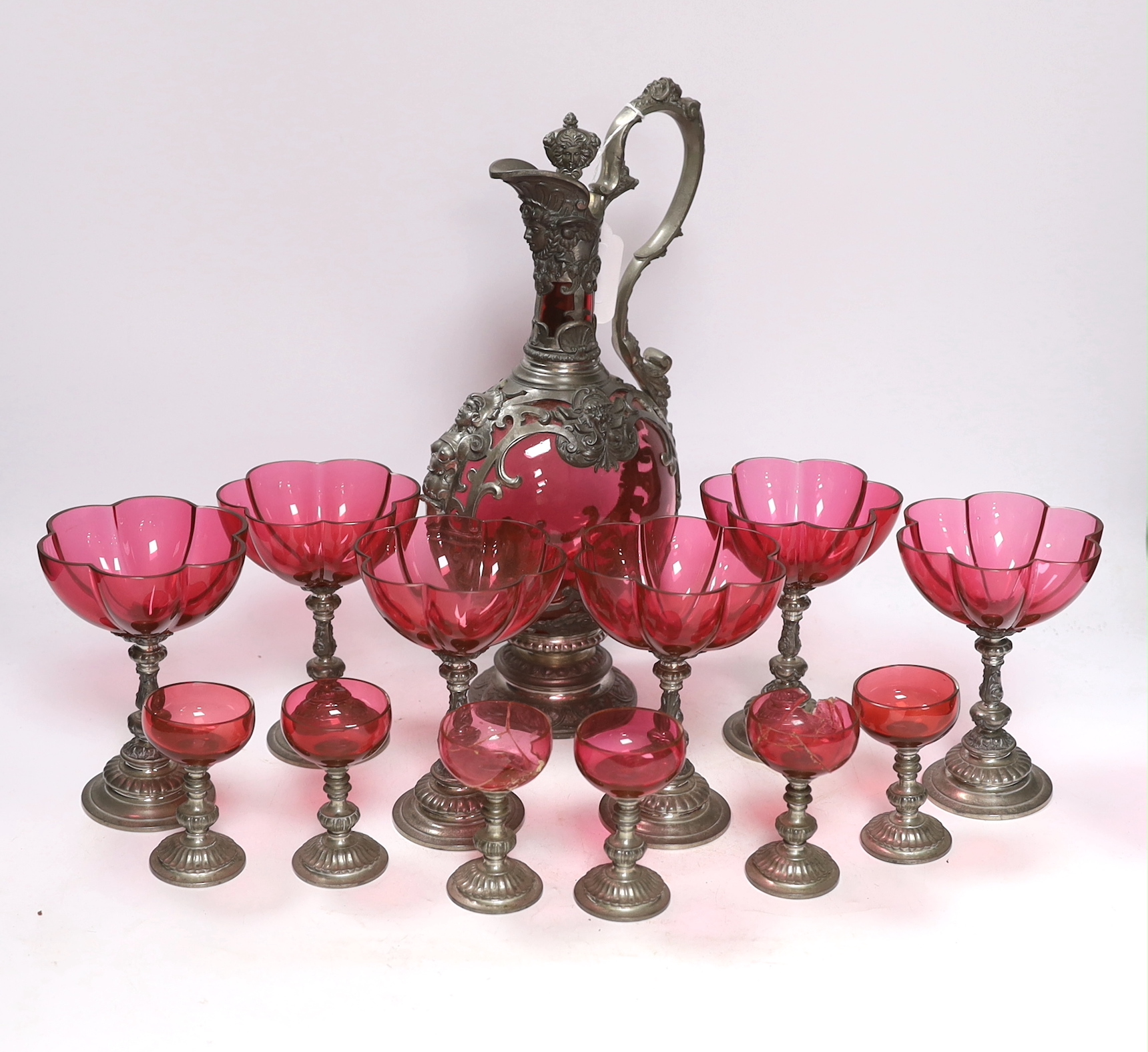 A Bohemian style pewter mounted cranberry glass ewer and twelve glasses, possibly Romanian, 33cm high
